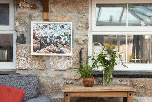 a painting on a wall with a table and a vase of flowers at Laity Vean Hideaway in Carbis Bay