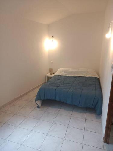 a small bedroom with a bed and a tiled floor at La Maison cévenole in Saint-André-de-Majencoules