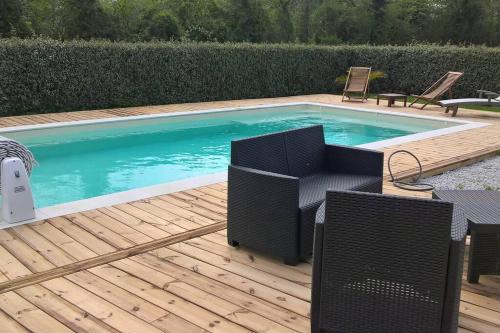 a swimming pool with chairs on a wooden deck at Camilena in Manvieux