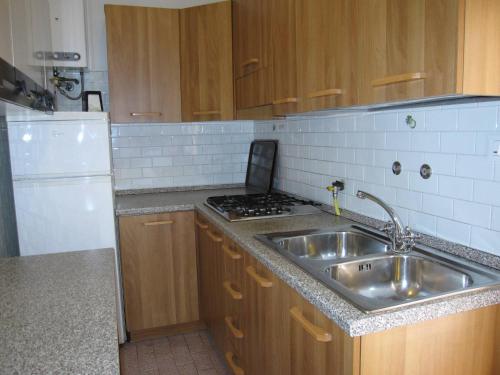 uma cozinha com um lavatório e um frigorífico branco em Seaview flat with unforgettable terrace! - Beahost em Grado-Pineta