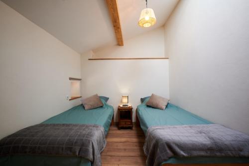 una habitación con dos camas y una mesa con lámpara en La Mottinière, en Saint-Hilaire-du-Rosier