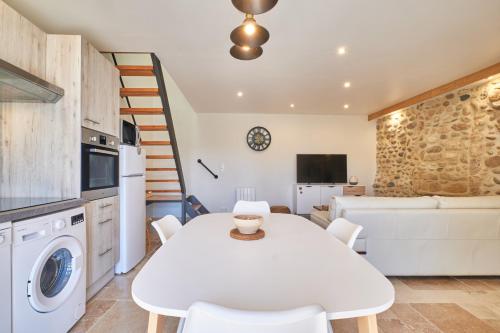 una cucina e un soggiorno con tavolo e sedie bianchi di La Mottinière a Saint-Hilaire-du-Rosier