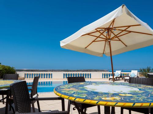 a table with an umbrella next to a pool at Villa Palma - Sunset Sea Views with Pool, Jacuzzi, Sauna and Games Room in Mellieħa