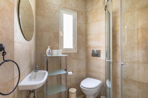 y baño con aseo, lavabo y ducha. en Villa Palma - Sunset Sea Views with Pool, Jacuzzi, Sauna and Games Room, en Mellieħa