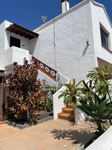 una casa blanca con algunas plantas delante de ella en Apartamento con amplia terraza en la playa, en Puerto del Carmen