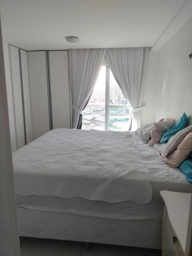 a bedroom with a large bed with a window at Quartos - Cíntia in Fortaleza