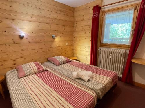 two beds in a room with wooden walls at Appartement proche des pistes avec terrasse sud - FR-1-411-687 in Les Allues