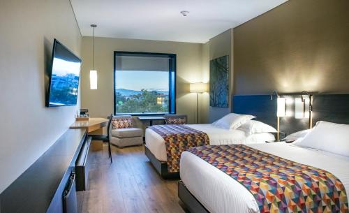 ボゴタにあるCité Hotelのベッド2台とデスクが備わるホテルルームです。