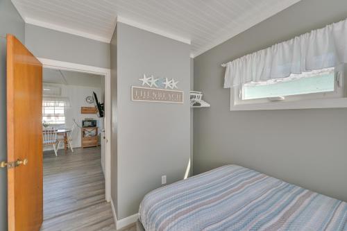 1 dormitorio con cama, ventana y pasillo en Charming Hampton Home with Porch, Walk to Beach!, en Hampton