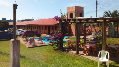 un patio trasero con piscina y pérgola en Pousada Angel's It, en Torres