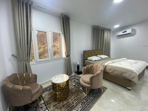 a bedroom with two beds and two chairs at استراحة الشرف ALSHARAF in Al ‘Aqar