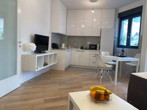 a kitchen with white cabinets and a bowl of fruit on a table at Apartman PORTO in Trebinje