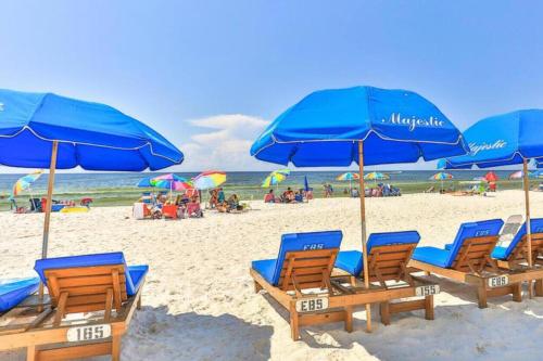 a group of blue beach chairs and umbrellas on a beach at Beachfront Studio #1112 at Majestic in Panama City Beach