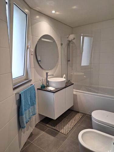 a bathroom with a sink and a toilet and a mirror at Coliseum Residence in Ponta Delgada
