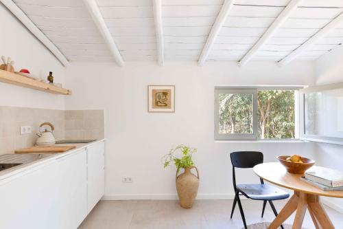 a kitchen with white walls and a table and chairs at Âmago Guesthouse in Santa Bárbara de Nexe