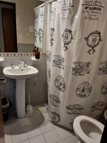 a bathroom with a shower curtain with a sink and a toilet at Alquiler Temporario en Nueva Córdoba! in Cordoba