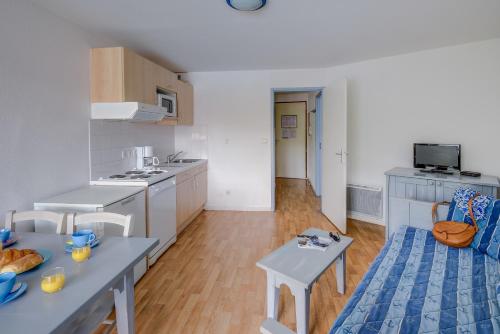 a kitchen with white cabinets and a table and chairs at Vacancéole - Les Jardins de l'Amirauté in Les Sables-dʼOlonne