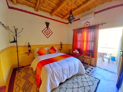 1 dormitorio con cama y ventana grande en Maison d'Hôte Argana, en Aït Idaïr