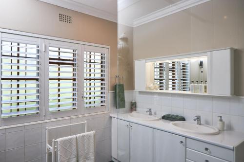 un bagno bianco con due lavandini e due finestre di Meerendal Cottage-Affordable Luxury-Private Garden with Pool & Hot Tub a Città del Capo