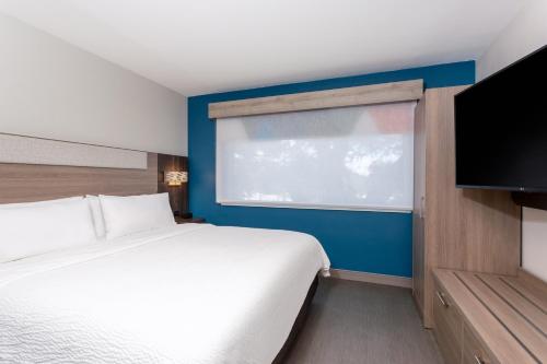 a bedroom with a white bed and a large window at Holiday Inn Express Hotel Clearwater East - ICOT Center by IHG in Pinellas Park