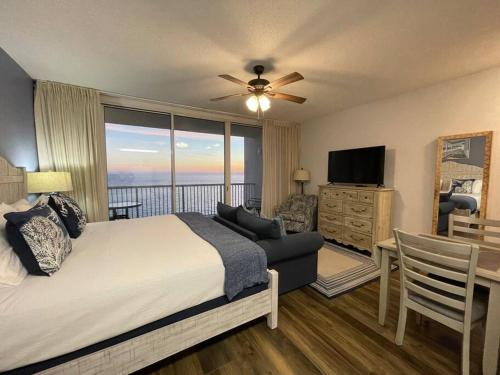 a bedroom with a bed and a balcony with a television at Beachfront Studio #909 at Majestic in Panama City Beach