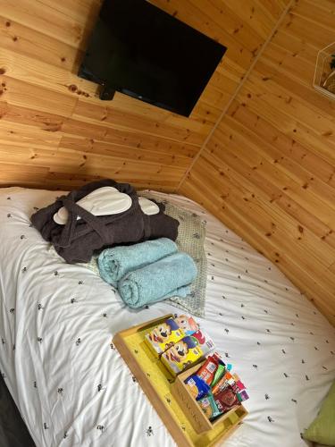 a room with a bed with towels and a tv at Heron Leap in Knaresborough