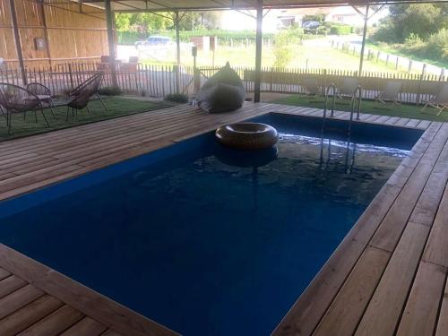 une piscine bleue avec une terrasse en bois dans l'établissement LE PETIT MONTY Gite Côté Jardin, à Saint-Malo-du-Bois