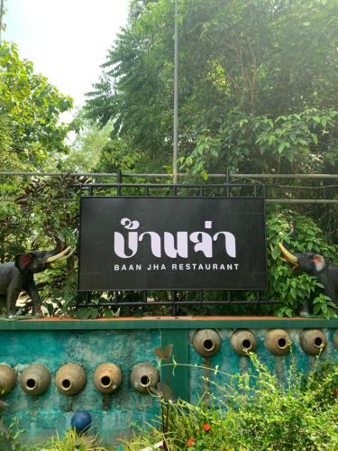 a sign for a zoo with two statues of elephants at Krua Chehe Resort ครัวเจ๊ะเห รีสอร์ท in Ban Khok Muang
