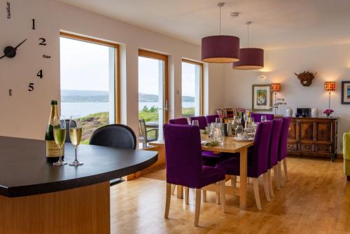a dining room with a table and purple chairs at Shore Croft in Aultbea
