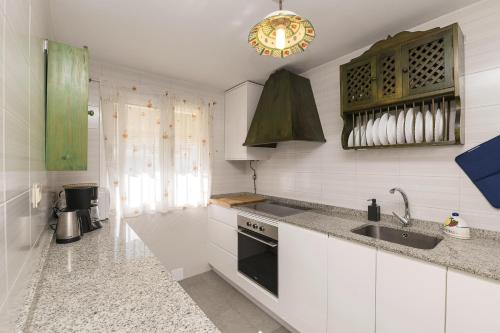 a white kitchen with a sink and a stove at Casa Ocon in Conil de la Frontera