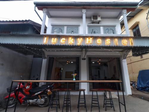 een motorfiets geparkeerd buiten een restaurant met een bord bij Lucky hostel in Luang Prabang