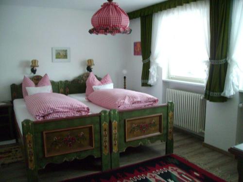 um quarto com 2 camas com almofadas cor-de-rosa e um lustre em Ferienhaus-Becker-Schmidt em St. Blasien