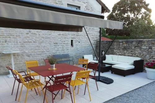a patio with a table and chairs and an umbrella at Bienvenue au Gite La So Sweet in Rully