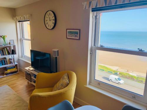 a living room with a large window and a yellow chair at North Sea View Apartment in Scarborough