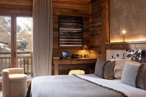 a bedroom with a bed and a desk with a laptop at M Lodge & Spa in Saint-Martin-de-Belleville