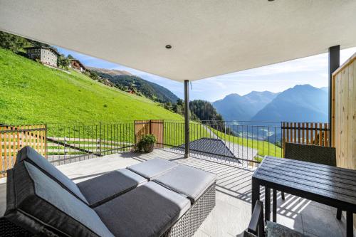 a balcony with a couch and a table and mountains at Sunnseitn Lodge Apartment Alps in Stulles