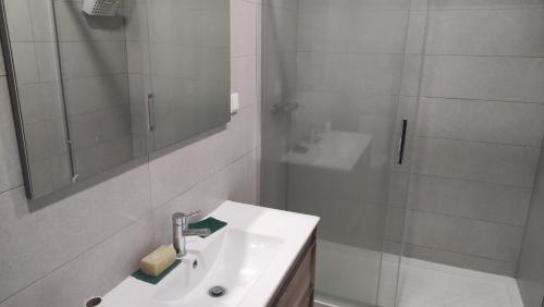 a white bathroom with a sink and a shower at Parede beach in Almada