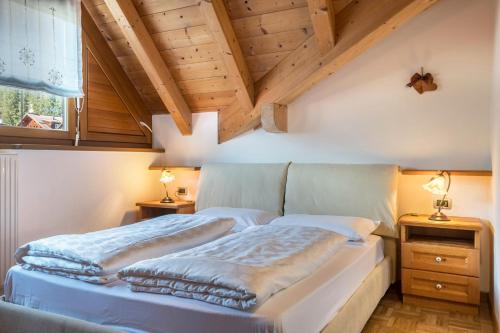 a bedroom with two beds and a wooden ceiling at Villa Lory 6 in Canazei