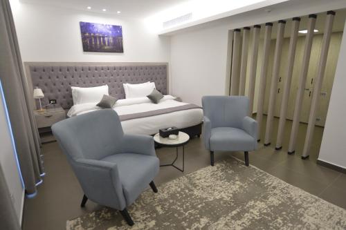 a bedroom with a bed and two blue chairs at Zett hotel in Jounieh