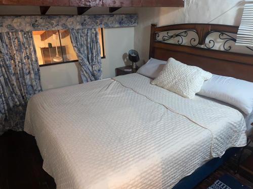 a bedroom with a white bed with a wooden headboard at Country San Bernardino in San Bernardino