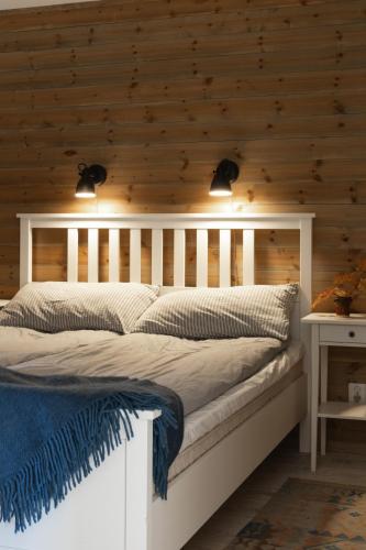 a bedroom with a white bed with a wooden wall at Skoogs Logi Lägenheter in Funäsdalen