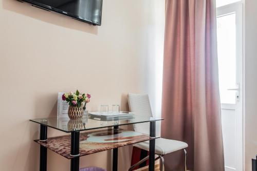 a glass table with a vase of flowers on it at Star Rent Hotel in Chişinău