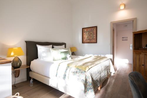 a bedroom with a large bed with white sheets at Hôtel Font Mourier in Cogolin