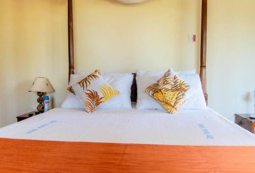 a bedroom with a large bed with white sheets and pillows at Sand and Shells Beach House- 4 Bedroom with a pool in Mombasa