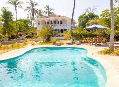 a swimming pool in front of a house at Sand and Shells Beach House- 4 Bedroom with a pool in Mombasa