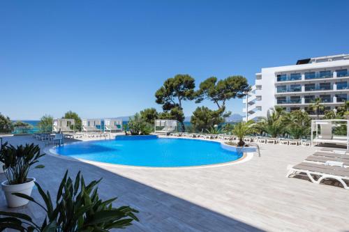 a swimming pool in a resort with chairs and a building at Hotel Best Punta Dorada in Salou
