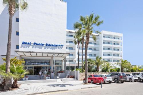 a building with palm trees in front of a parking lot at Hotel Best Punta Dorada in Salou