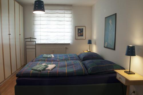 sypialnia z łóżkiem z niebieską kołdrą i oknem w obiekcie Ferienwohnung Henniger w Dreźnie