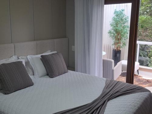a bedroom with a white bed with pillows and a window at Locanda Montecielo Pousada Boutique - Vale dos Vinhedos in Bento Gonçalves