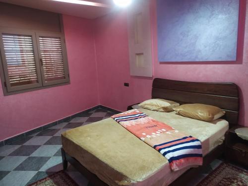 1 dormitorio con 2 camas y pared de color rosa en شقق فندقية بن خليل /hôtel appartements Bin khlil, en Tan-Tan